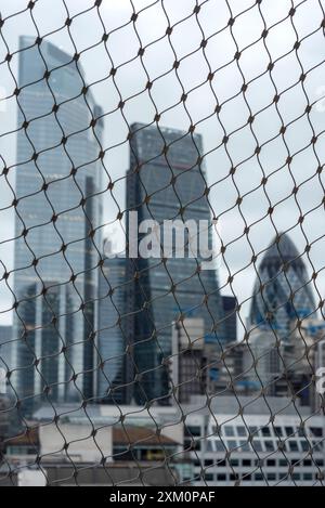 Vue imprenable et inhabituelle des bâtiments de la City de Londres à travers des clôtures en treillis métallique depuis le sommet du Monument à Londres, GB, Royaume-Uni Banque D'Images