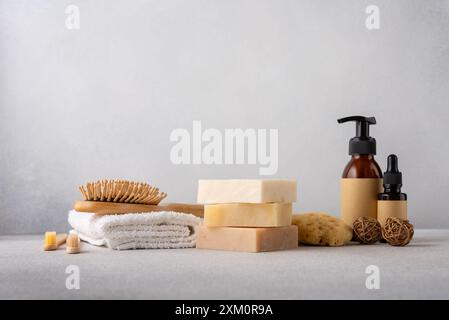 Pile de pains de savon bio, peigne à cheveux en bambou, bouteilles cosmétiques, éponge naturelle et serviette en coton. Salle de bain et concept de bien-être. Banque D'Images