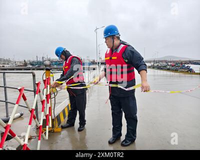 (240725) -- NINGDE, 25 juillet 2024 (Xinhua) -- des membres du personnel d'urgence sont en garde contre le typhon Gaemi dans un port du canton de Sansha dans le comté de Xiapu, province du Fujian, au sud-est de la Chine, le 25 juillet 2024. La province du Fujian, dans l'est de la Chine, avait relocalisé 156 800 résidents à 7 heures jeudi à l'approche du typhon Gaemi, le troisième typhon de cette année, ont déclaré les autorités locales. Entre-temps, 73 traversées de traversiers le long de la côte de la province ont été suspendues et 97 vols ont été annulés. Plus de 29 000 personnes travaillant sur des radeaux de pêche le long de sa côte ont été évacuées vers le rivage, et 733 bateaux de pêche HAV Banque D'Images