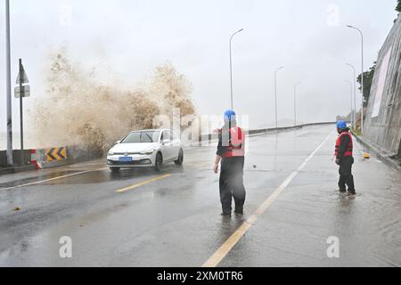 (240725) -- NINGDE, 25 juillet 2024 (Xinhua) -- des membres du personnel d'urgence guident une voiture bloquée vers une zone sûre alors que d'énormes vagues battent le rivage dans le canton de Sansha du comté de Xiapu, dans la province du Fujian, au sud-est de la Chine, 25 juillet 2024. La province du Fujian, dans l'est de la Chine, avait relocalisé 156 800 résidents à 7 heures jeudi à l'approche du typhon Gaemi, le troisième typhon de cette année, ont déclaré les autorités locales. Entre-temps, 73 traversées de traversiers le long de la côte de la province ont été suspendues et 97 vols ont été annulés. Plus de 29 000 personnes travaillant sur des radeaux de pêche le long de sa côte ont été évacuées vers le rivage, et 7 Banque D'Images