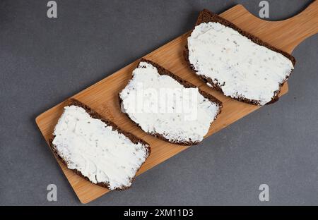 Pain de seigle fait maison sur une planche à découper en bois avec du fromage caillé et de la ricotta Banque D'Images