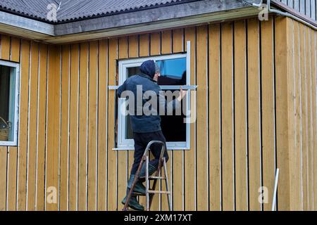 Finition extérieure de la façade de la maison à ossature, le constructeur installe des montants métalliques sur les fenêtres. Banque D'Images