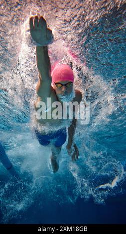 Le nageur masculin sportif a capturé une course de mi-nage libre sous l'eau, affichant force et technique en piscine pendant l'entraînement. Banque D'Images