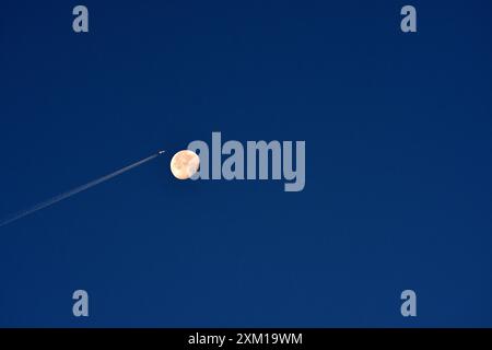 Marseille, France. 24 juillet 2024. Un avion avec sa traînée de carburant passe à travers le ciel avec la lune derrière lui. (Photo Gerard Bottino/SOPA images/SIPA USA) crédit : SIPA USA/Alamy Live News Banque D'Images