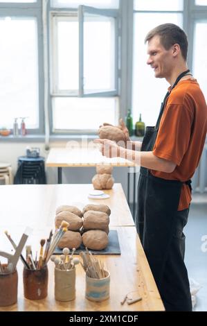 Potter pétrit l'argile avant de l'utiliser dans l'atelier. Photo verticale. Banque D'Images