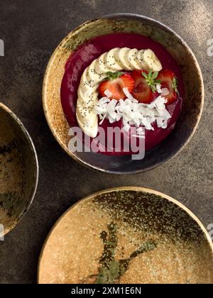 Bol à smoothie avec des flocons de banane, de fraise et de noix de coco, joliment décoré. Banque D'Images