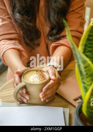 Mains de femme tenant une tasse de café sur la table en bois. Banque D'Images