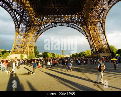 Touristes marchant sous la Tour Eiffel. Paris. Banque D'Images