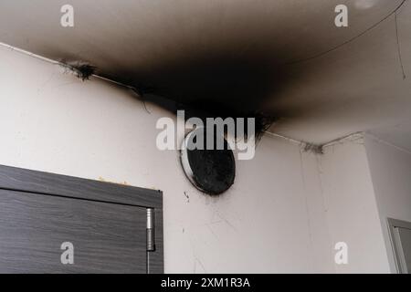 Lampe LED grillée. Une lampe d'abat-jour sur le mur après un incendie. Combustion spontanée et incendie dans un immeuble résidentiel. Accident intérieur Banque D'Images