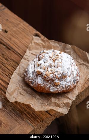 Pain aux cacahuètes fraîchement cuit avec du sucre glace sur du papier sulfurisé, sur une table en bois. Banque D'Images