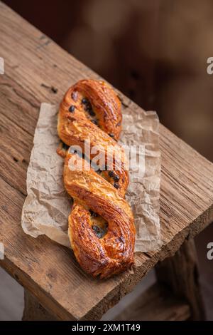 Pâtisserie tressée à la main avec chocolat et crème anglaise, sur papier parchemin. Fond en bois. Vue de dessus Banque D'Images