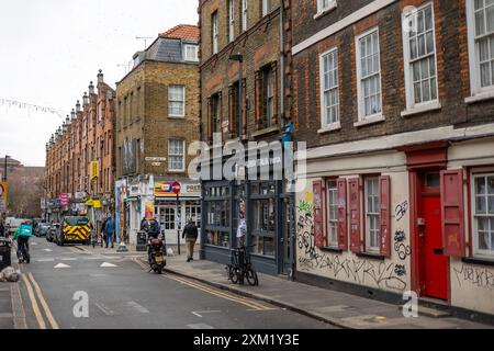 Les piétons marchent devant les murs couverts de graffiti, Londres Banque D'Images