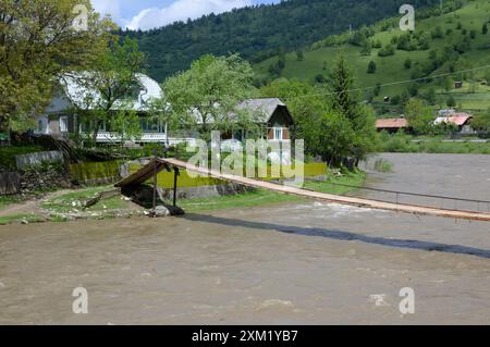 Passerelle suspendue à travers la rivière à débit rapide dans les Carpates, Roumanie Banque D'Images