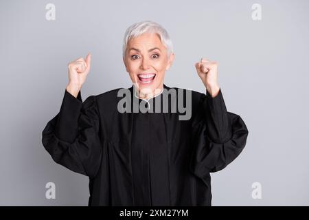 Photo de la vieille femme excitée juge lever les poings vers le haut de la cour de gagner le procès isolé fond de couleur grise Banque D'Images