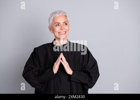 Photo de la vieille dame smilign juge mettre les doigts ensemble regarder l'espace vide isolé fond de couleur grise Banque D'Images