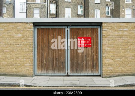 pas de parking devant ces portes signe, dans earls court, londres angleterre, avec les fenêtres des maisons mitoyennes en arrière-plan Banque D'Images