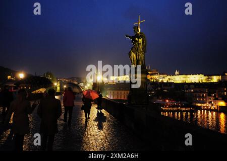 Parapluie rouge dans la nuit sombre et la pluie sur le pont Charles, les gens. Statues, la croix, le château - Karlův plus sur la rivière Vltava, Prague. Banque D'Images