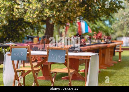 Configuration de réception de mariage en plein air avec des signes Mr. et Mrs. sur des chaises sous un arbre Banque D'Images