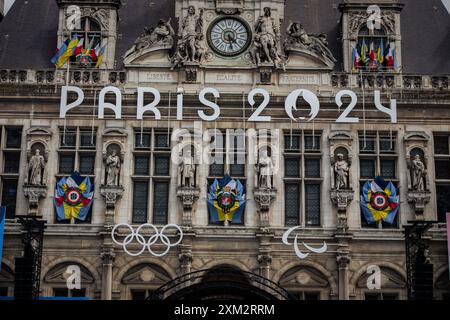 Paris, France. 23 juillet 2024. La façade du bâtiment de l’Hôtel de ville de Paris est décorée pour les Jeux Olympiques et Paralympiques de Paris. A quelques jours de l’inauguration inédite des Jeux Olympiques de Paris, qui se dérouleront sur 6 kilomètres de Seine, la ville lumière se métamorphose. Des garde-corps ont été installés autour du périmètre très restreint de la zone où aura lieu la cérémonie d’ouverture, de sorte que vous pouvez voir des rues complètement vides, ainsi que des terrasses de cafés et de restaurants. Crédit : SOPA images Limited/Alamy Live News Banque D'Images