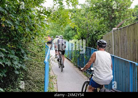 Un groupe de cyclistes âgés chevauchant et bloquant une étroite passerelle publique au bord de la rivière à Walton on Thames Surrey Angleterre Banque D'Images