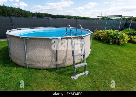 Grande piscine d'expansion d'un diamètre de 3,96 mètres, placée dans la cour sur l'herbe. Banque D'Images