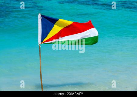 Drapeau des Seychelles sur une plage, fond d'eau turquoise Banque D'Images