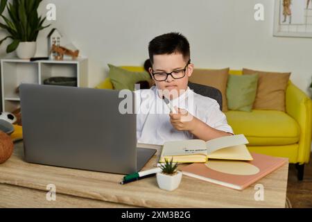 Un jeune garçon avec des études sur le syndrome de Down à la maison, intentionnellement concentré sur son travail. Banque D'Images