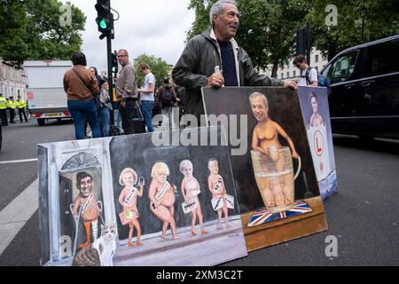 L'artiste politique Kaya Mar avec ses dernières peintures devant Downing Street le jour où les conservateurs sortants sont remplacés par un gouvernement travailliste le 5 juillet 2024 à Londres, Royaume-Uni. Le Parti travailliste a remporté les élections générales avec une victoire écrasante, rapprochant à sa fin le gouvernement conservateur qui est au pouvoir depuis 14 ans. Sur Whitehall, l'ambiance était celle de la célébration. Banque D'Images