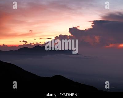 Le ciel est d'une belle couleur orange lorsque le soleil se couche. Les nuages sont blancs et moelleux, créant une atmosphère paisible et sereine Banque D'Images