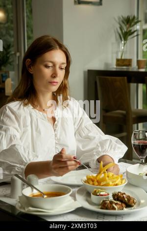 Femme mangeant des frites servies sur la table du restaurant Banque D'Images