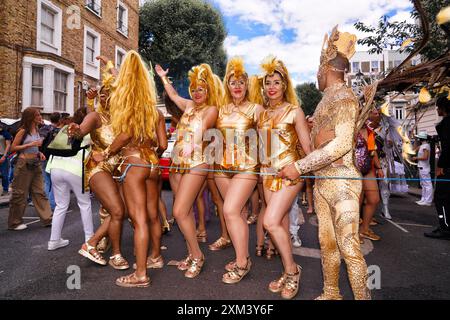 Carnaval de Notting Hill à Londres, Royaume-Uni : un groupe d'artistes de carnaval en costumes dorés dans la rue Banque D'Images