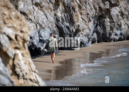 jeune homme portant un grand sac à dos le long d'une plage rocheuse sur l'île grecque de zante ou zakynthos en grèce, Banque D'Images