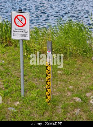 Strausberg, Allemagne. 25 juillet 2024. Un indicateur de niveau d'eau sur le lac Straus a longtemps été sec. Le lac a perdu la moitié de son eau depuis une dizaine d'années. Depuis 2014, le niveau de l'eau a baissé d'environ 20 centimètres chaque année. La cause de la perte d'eau est inconnue. En raison de toutes les pluies de l'hiver dernier et aussi cet été, le niveau du lac Straus a augmenté d'environ dix centimètres pendant de nombreuses années. Crédit : Patrick Pleul/dpa/Alamy Live News Banque D'Images