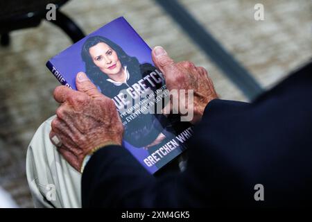 East Lansing, États-Unis. 23 juillet 2024. Un membre du public détient un exemplaire de True Gretch lors d'un arrêt sur la tournée de livres du gouverneur Gretchen Whitmer à East Lansing, Mich., le 23 juillet 2024. (Photo de Andrew Roth/Sipa USA) crédit : Sipa USA/Alamy Live News Banque D'Images