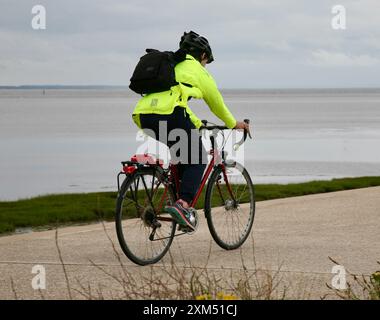 Une jeune dame faisant du vélo le long de la promenade, au bord de l'eau. Banque D'Images