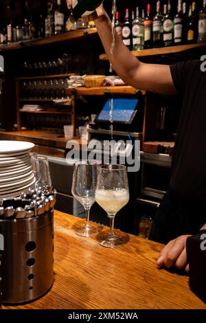 Versement spécial de txakoli ou chacolí vin blanc légèrement mousseux très sec dans des verres, produit dans le pays basque espagnol dans le bar pinchos typique Banque D'Images