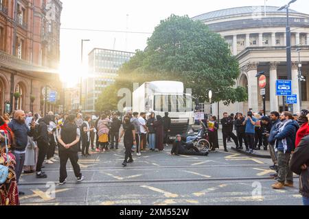 Manchester, Royaume-Uni. 25 JUILLET 2024. Des activistes bloquent la route et le tramway alors que les manifestants se rassemblaient pour manifester contre une vidéo diffusée depuis l'aéroport de Manchester dans laquelle des agents des armes à feu du GMP ont été vus en train d'utiliser la force contre des manifestants, l'incident étant transmis au GIEC. Les manifestants ont bloqué les tramways et la circulation à St Peters Square sans intervention de la police. Les manifestants se sont dispersés après environ 2 heures. Crédit Milo Chandler/Alamy Live News Banque D'Images