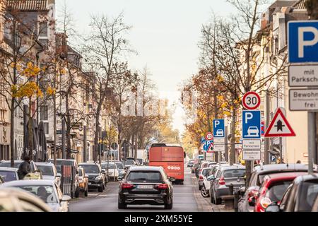 Rue de Troisdorf, Allemagne, avec des voitures garées et un bus de passage. L'image capture la scène urbaine, mettant en valeur les transports et les infrastructures de la ville Banque D'Images