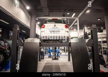 Cette photo montre une voiture en cours d'inspection technique dans un atelier de mécanicien à Belgrade, en Serbie. Le véhicule est soulevé sur une plate-forme, et le GA Banque D'Images