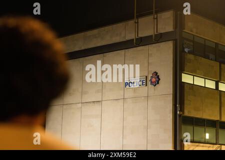 Rochdale, Royaume-Uni. 25 JUILLET 2024. Le manifestant regarde vers le poste de police de Rochdale alors que les manifestants jetaient des œufs et provoquaient des désordres lors d'une manifestation contre une vidéo diffusée depuis l'aéroport de Manchester dans laquelle des agents des armes à feu du GMP avaient été vus en train d'utiliser la force contre des manifestants, l'incident ayant été transmis au GIEC. Crédit Milo Chandler/Alamy Live News Banque D'Images