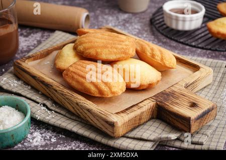 Planche en bois avec madeleines sur fond gris Banque D'Images