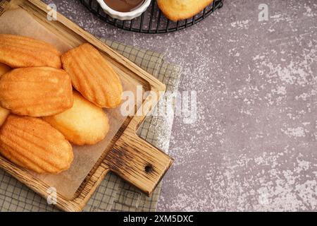 Planche en bois avec de délicieuses madeleines sur fond gris Banque D'Images