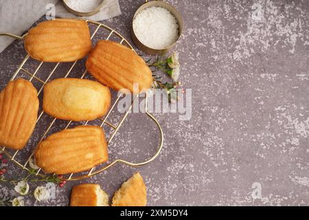 Composition avec de savoureuses madeleines et bol avec des flocons de noix de coco sur fond gris Banque D'Images