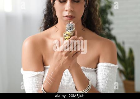 Belle chaman féminin afro-américain avec des herbes effectuant un rituel à la maison Banque D'Images