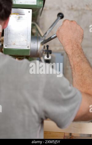 Carpenter utilise une machine à bois dans un atelier, démontrant la combinaison de l'artisanat traditionnel et de la technologie moderne Banque D'Images