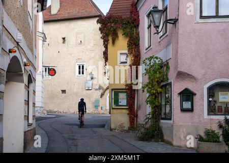 Wachau, Autriche - 26 octobre 2023 : Un cycliste descend une rue étroite de Wachau, Autriche, bordée de bâtiments historiques et de verdure luxuriante. Banque D'Images