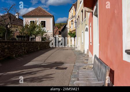 Wachau, Autriche - 26 octobre 2023 : Une étroite rue pavée à Wachau, Autriche, bordée de bâtiments colorés et d'un banc en bois. Banque D'Images