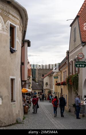 Wachau, Autriche - 26 octobre 2023 : rue pavée à Wachau, Autriche, bordée de bâtiments historiques et de gens qui marchent. Banque D'Images