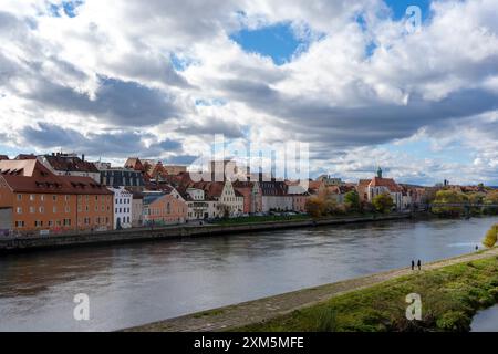 Ratisbonne, Allemagne - 06 novembre 2023 : Ratisbonne, Allemagne, présente une rivière avec un chemin de pierre et une herbe verte luxuriante. Un ciel nuageux au-dessus d'un ciel de ville Banque D'Images