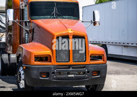 Qualité industrielle fraîchement peinte après réparation orange Big Rig semi-camion avec son extrémité avant démontée des phares manquants et la calandre se trouve avec une charge Banque D'Images